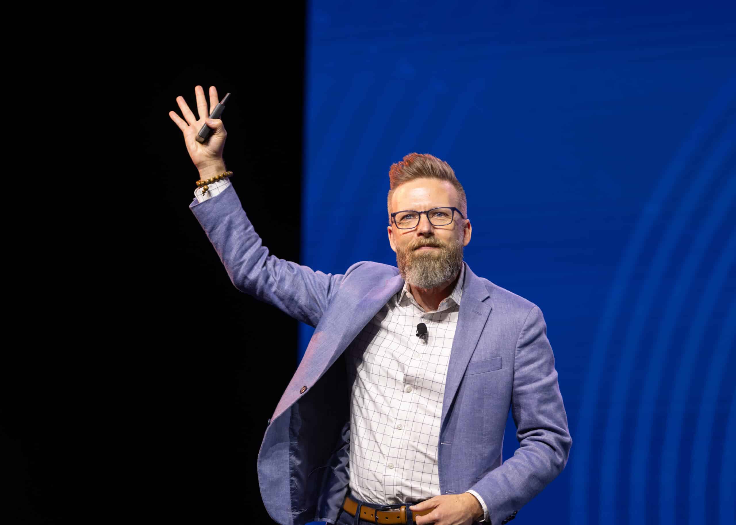 Shawn Ellis speaking on stage with one hand raised